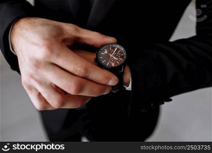 businessman looks at the watch on his wrist, looks at the time. High quality photo.. businessman looks at the watch on his wrist, looks at the time. High quality photo
