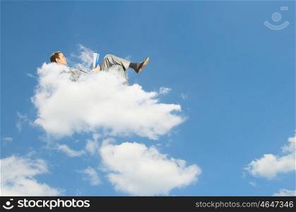 Businessman lying on clouds. Image of businessman lying on clouds with tablet pc