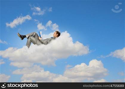 Businessman lying on clouds. Image of businessman lying on clouds with tablet pc