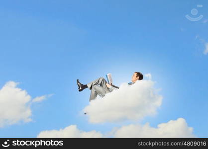 Businessman lying on clouds. Image of businessman lying on clouds with tablet pc