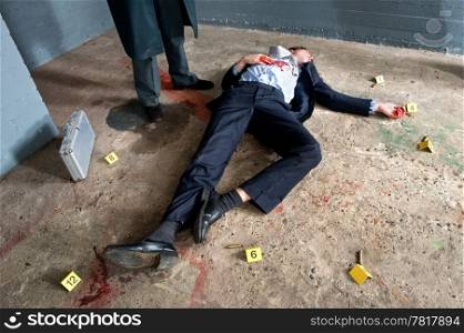 Businessman lying on the concrete floor of a basement, being shot, surrounded by evidence placards, and a man wearing a long overcoat hovering over the body