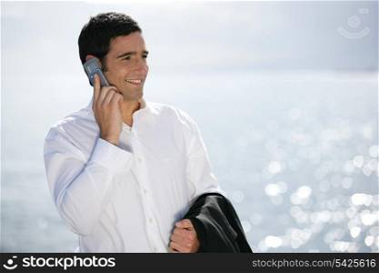 Businessman making call at the beach