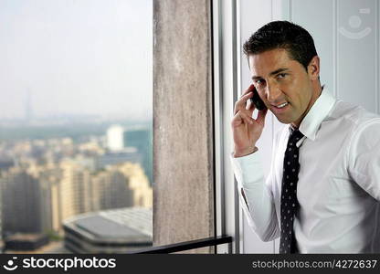 Businessman making call by window