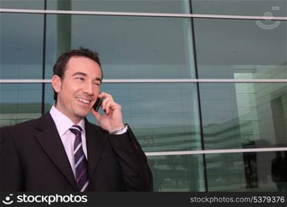 Businessman making call whilst stood outside office