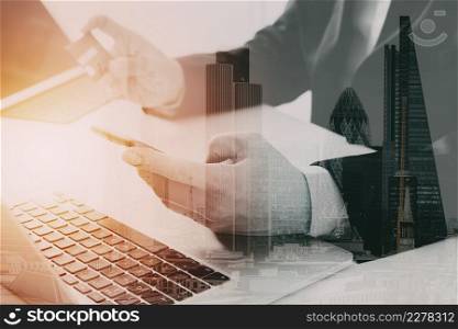 businessman making credit card purchase online with mobile phone and laptop computer on modern desk with city exposure