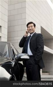 businessman making phone call beside the car