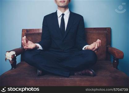 Businessman meditating on a sofa