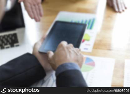 businessman meeting, analyzing and discussing with tablet and paperwork document - blur for use as background