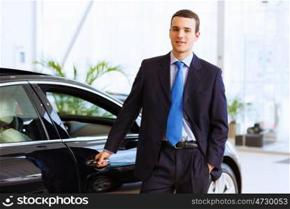 Businessman near car. Image of handsome young businessman in suit standing near car
