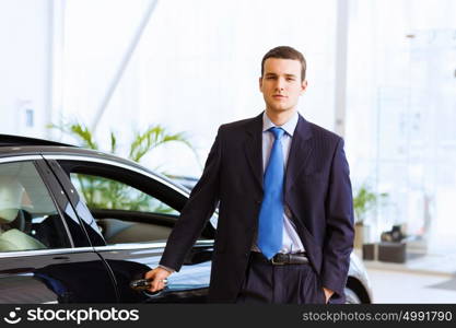 Businessman near car. Image of handsome young businessman in suit standing near car