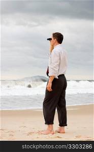 Businessman on a beach searching with binoculars