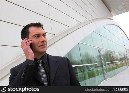 Businessman on a cellphone outside a modern building