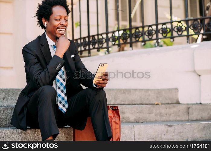 Businessman on a video call with his mobile phone while sitting on stairs outdoors. Business and technology concept.