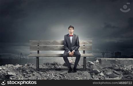 Businessman on bench. Young businessman sitting on bench with glasses in hands