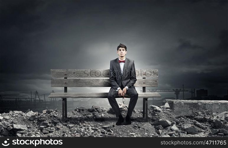 Businessman on bench. Young businessman sitting on bench with glasses in hands