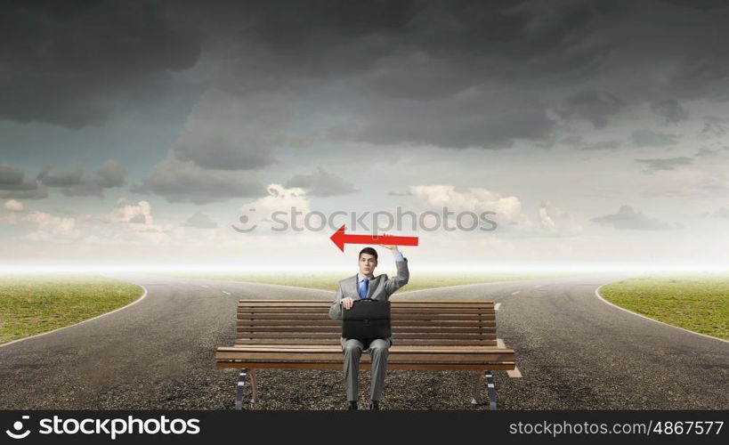 Businessman on bench. Young smiling businessman sitting on bench with briefcase and arrow in hand