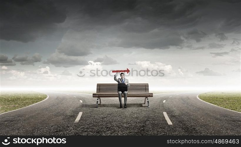 Businessman on bench. Young smiling businessman sitting on bench with briefcase and arrow in hand