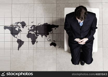 Businessman on chair. Top view of thoughtful businessman sitting on chair