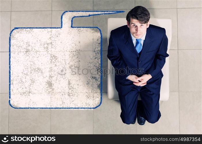 Businessman on chair. Top view of thoughtful businessman sitting on chair