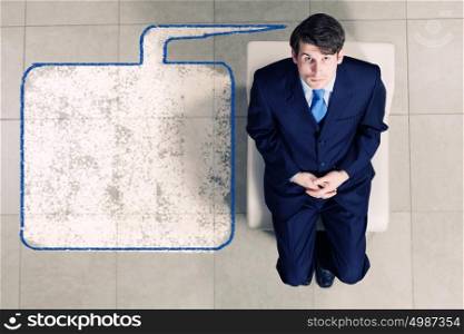 Businessman on chair. Top view of thoughtful businessman sitting on chair