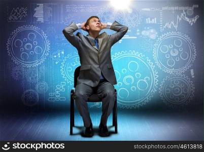 Businessman on chair. Young businessman sitting on chair and looking above