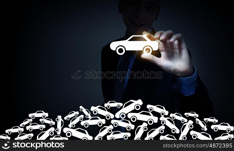 Businessman on dark background taking with fingers car icon. Man choosing car sign