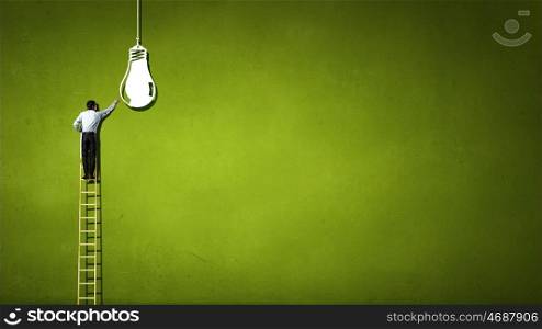 Businessman on ladder. Back view of businessman standing on ladder and reaching light bulb