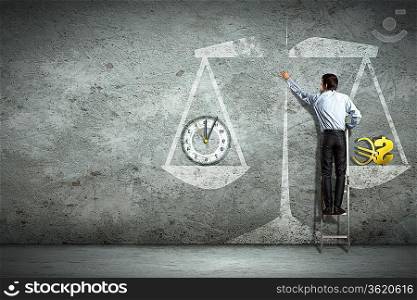Businessman on ladder pointing at scale picture