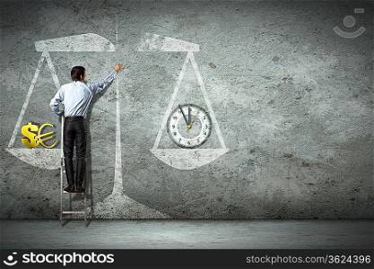 Businessman on ladder pointing at scale picture