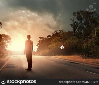 Businessman on road. Rear view of businessman standing on road