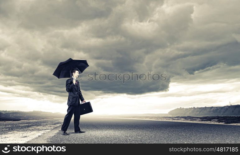 Businessman on road. Young handsome businessman standing on asphalt road