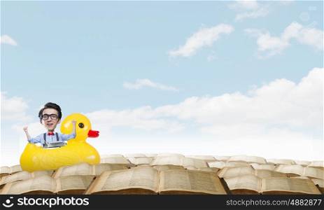 Businessman on rubber duck. Young happy businessman riding yellow rubber duck