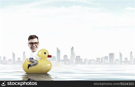 Businessman on rubber duck. Young happy businessman riding yellow rubber duck