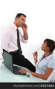 Businessman on the phone and businesswoman sitting at a desk