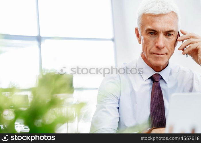 Businessman on the phone sitting at the computer in his office. Being connected and in touch