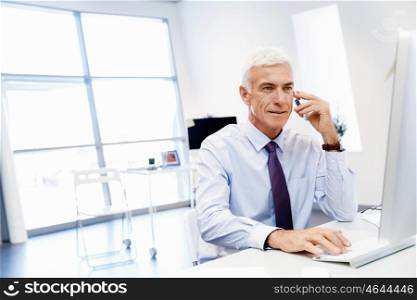 Businessman on the phone sitting at the computer in his office. Being connected and in touch