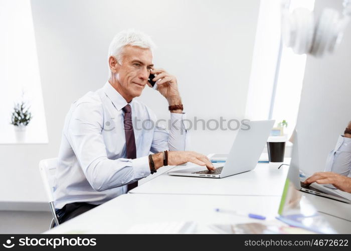 Businessman on the phone sitting at the computer in his office. Being connected and in touch