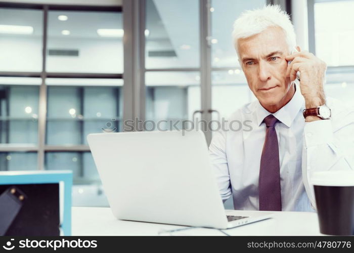 Businessman on the phone sitting at the computer in his office. Being connected and in touch