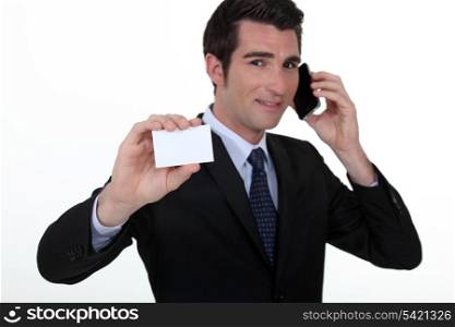 Businessman on the phone whilst showing a blank card