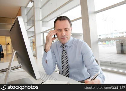 Businessman on the phone writing on agenda