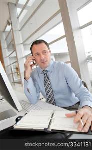 Businessman on the phone writing on agenda