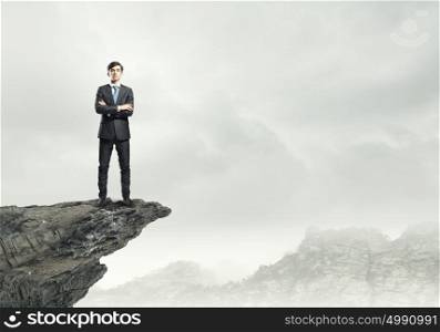 Businessman on top. Confident businessman standing on top of rock