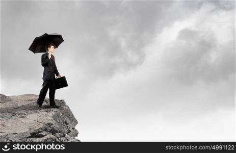 Businessman on top. Confident businessman standing on top of rock