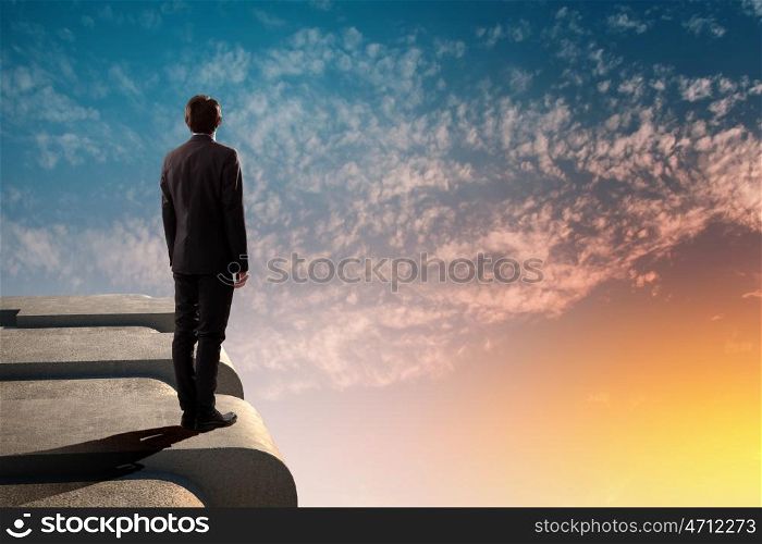 Businessman on top of building. Image of young businessman standing on top of building