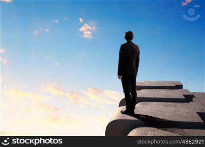 Businessman on top of building. Image of young businessman standing on top of building