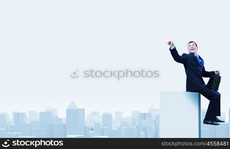 Businessman on top. Young businessman with suitcase sitting on roof of building