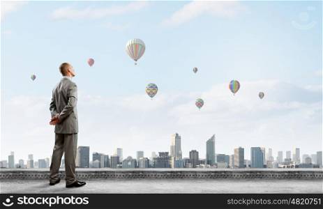 Businessman on top. Young handsome businessman standing on top of building