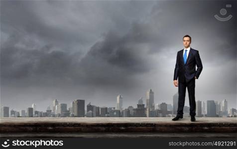 Businessman on top. Young handsome businessman standing on top of building