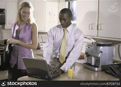 Businessman operating a laptop with a businesswoman standing beside him