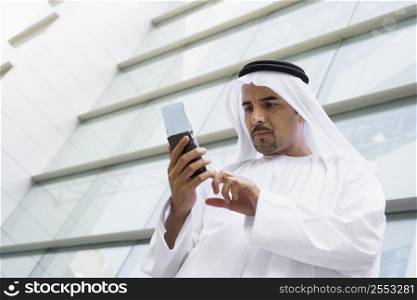 Businessman outdoors by building using PDA